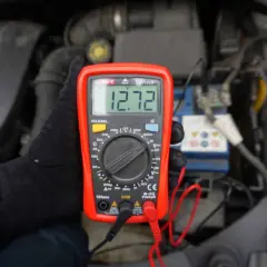 Multimetr pokazuje 12.72V. Sprawdzam, ile volt powinien ładować alternator, by upewnić się, że akumulator jest w dobrym stanie.