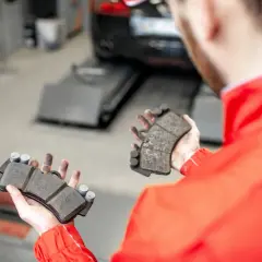 Mechanik pokazuje klocki hamulcowe, przygotowując się do odpowietrzenia hamulców z ABS.