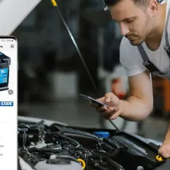 Mechanik sprawdza na telefonie, ile kosztuje nowy akumulator samochodowy Exide EK700.