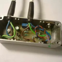 Schemat połączeń regulatora napięcia 12V. Widać płytkę drukowaną z elementami elektronicznymi i przewodami w metalowej obudowie.