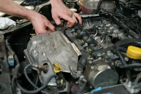 Mechanik sprawdza silnik, szukając objawów uszkodzonego czujnika położenia wałka rozrządu.