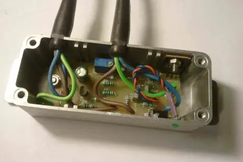 Schemat połączeń regulatora napięcia 12V. Widać płytkę drukowaną z elementami elektronicznymi i przewodami w metalowej obudowie.