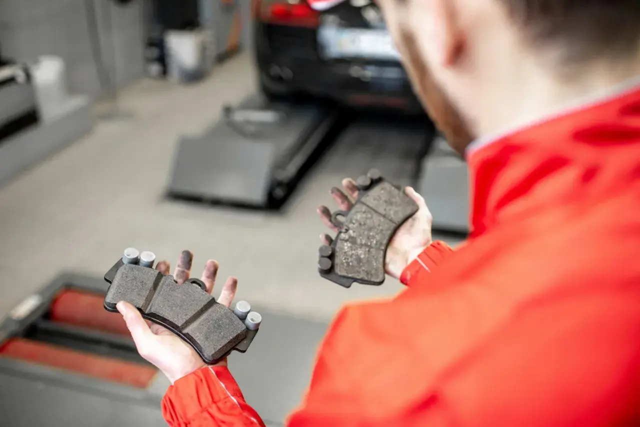 Mechanik pokazuje klocki hamulcowe, przygotowując się do odpowietrzenia hamulców z ABS.